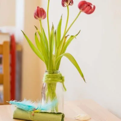 Tulpen in einem mit Wolle umwickelten Glas auf einem Tisch