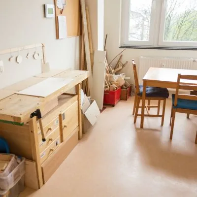 Werkraum mit Hobelbank, Holzvorrat und Arbeitstisch am Fenster